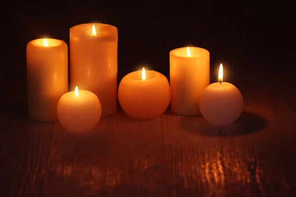 Burning candles on table in darkness — Stock Photo, Image