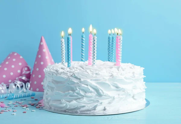 青い壁にテーブルの上のキャンドルで誕生日ケーキ — ストック写真