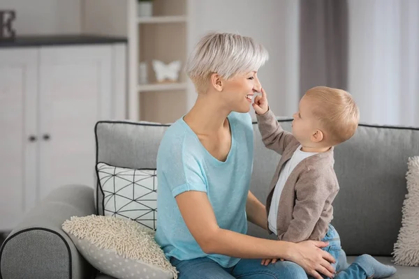 Приваблива молода мати грає зі своєю дитиною на дивані вдома — стокове фото