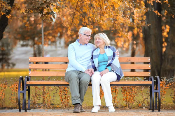 Bonito casal de idosos sentado no banco no parque de outono — Fotografia de Stock