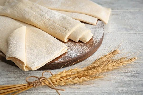 Board with fresh raw puff dough on wooden table — Stock Photo, Image