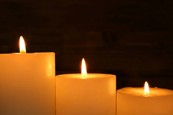 Восковые свечи горят на темном фоне, крупным планом — стоковое фото