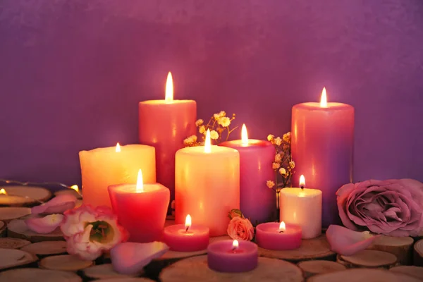 Candele viola ardenti con fiori sullo sfondo di colore — Foto Stock