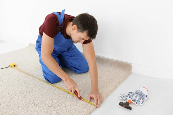 Worker using cutter while installing new carpet flooring in room — Stock Photo, Image