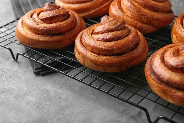 Support de refroidissement avec rouleaux de cannelle sucrée sur la table — Photo