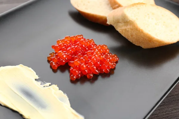 Placa con caviar rojo, mantequilla y pan en la mesa, primer plano —  Fotos de Stock