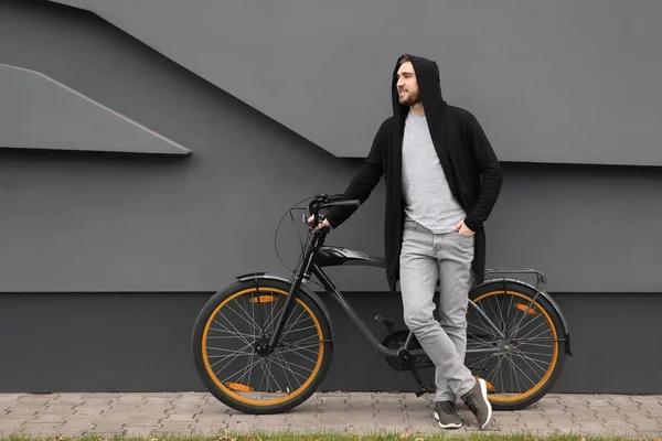 Schöner junger Hipster-Mann mit Fahrrad nahe Mauer im Freien — Stockfoto