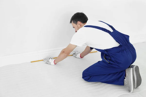 Worker with tape measure preparing to install new carpet flooring — Stock Photo, Image