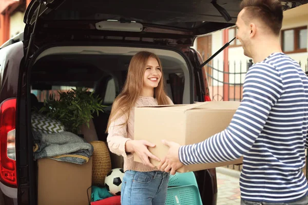 Jong paar lossen vakken van hun auto over het verplaatsen van de dag — Stockfoto