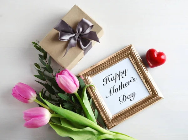 Caja de regalo, tulipanes rosados y marco de fotos con palabras "Feliz día de la madre" sobre fondo de madera claro — Foto de Stock