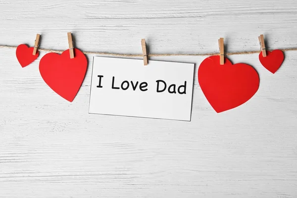 Card for Father's day and paper hearts on string against wooden background — Stock Photo, Image