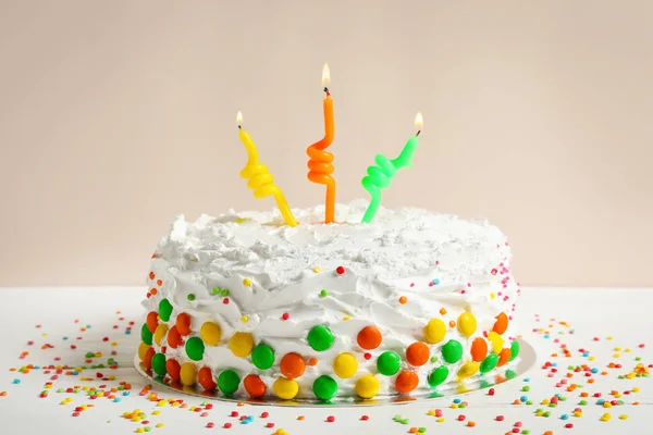 Tarta de cumpleaños con velas en la mesa contra la pared de luz — Foto de Stock