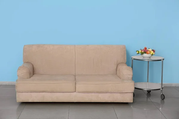 Stílusos kanapé, asztal mellett színes fal beltéri — Stock Fotó