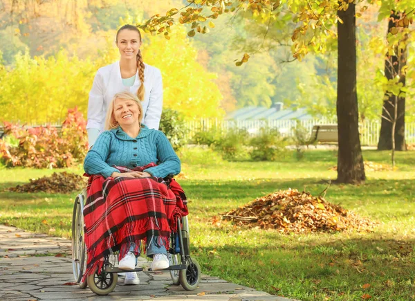 Fogyatékkal élő idősebb nő és a fiatal nővér a park — Stock Fotó