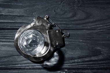 Cam ve koyu ahşap arka plan üzerinde kelepçe. Alkol bağımlılığı kavramı