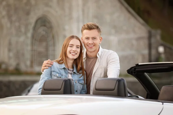 快乐的年轻夫妇站在近现代汽车户外 — 图库照片