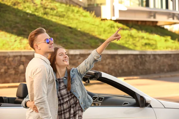 Heureux jeune couple debout près de la voiture moderne à l'extérieur — Photo