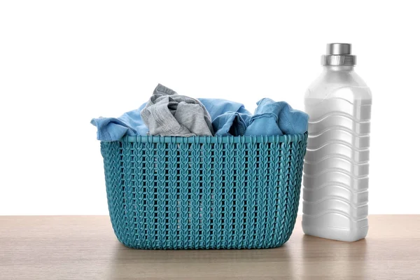 Basket with dirty clothes and laundry detergent on table against white background — Stock Photo, Image