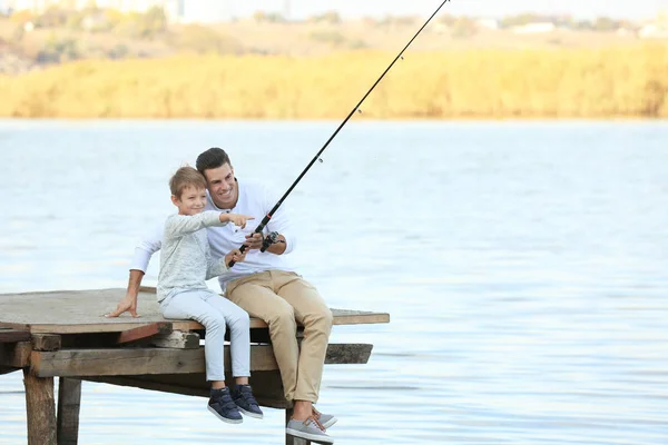 Padre y su hijo pescando desde el muelle en el río — Foto de Stock