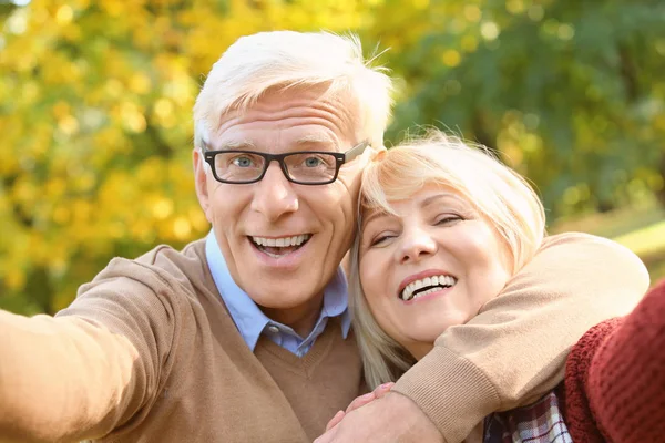 Bonito casal de idosos tomando selfie no parque de outono — Fotografia de Stock
