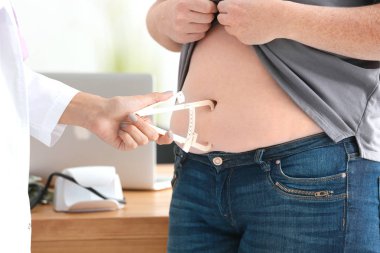 Genç kadın doktor şişman kilolu kadın Kliniği kumpas ile tabakası ölçme