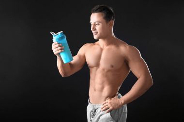 Sportif genç adam protein sallamak siyah arka plan üzerine