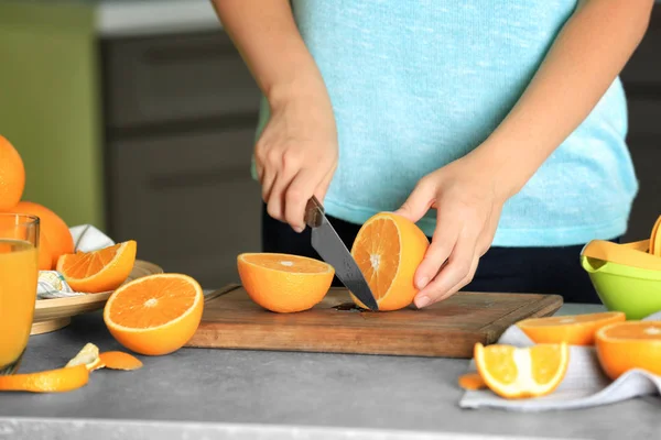 Mujer cortando naranja a bordo en la cocina — Foto de Stock