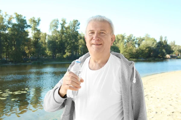 Homme mûr avec bouteille d'eau sur la plage — Photo