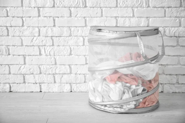 Basket with laundry on floor near brick wall — Stock Photo, Image