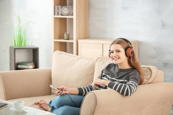 Hermosa mujer escuchando música mientras descansa en el sofá en casa —  Fotos de Stock