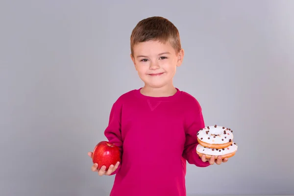 Мальчик Свежим Яблоком Сладкими Пончиками Сером Фоне — стоковое фото