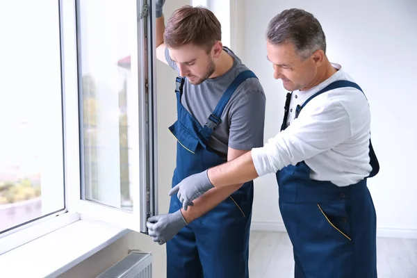 Construction worker with trainee installing window in house — Stock Photo, Image