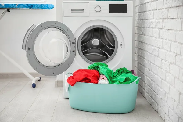 Mand met Wasserij en een wasmachine in de badkamer — Stockfoto