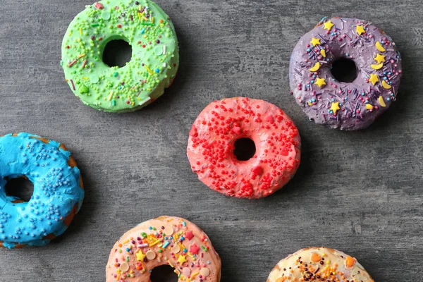 Donuts coloridos gostosos frescos no fundo cinza — Fotografia de Stock