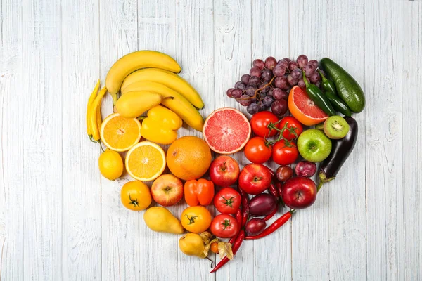 Creative composition made of fruits and vegetables in rainbow colors on wooden background, flat lay