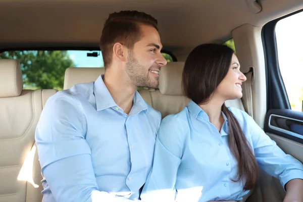 Bella giovane coppia seduta sul sedile posteriore in auto — Foto Stock