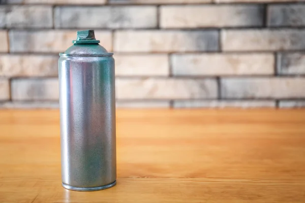 Aerosoldose aus Aluminium mit Farbe auf Holztisch gegen Ziegelwand — Stockfoto