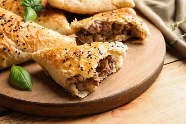 Placa de madeira com deliciosas samosas de carne na mesa — Fotografia de Stock