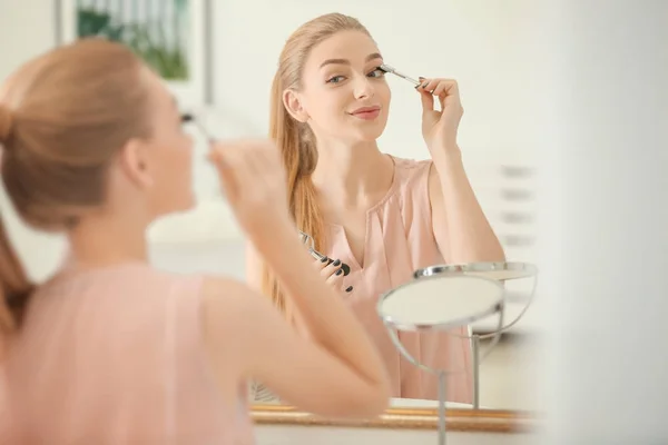 Bella giovane donna utilizzando pennello ciglia — Foto Stock