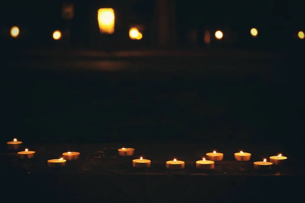 Muitas velas acesas na escuridão — Fotografia de Stock