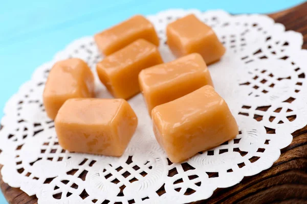 Wooden board with tasty caramel candies on table, closeup — Stock Photo, Image