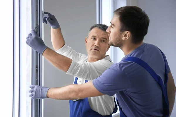 Construction worker with trainee installing window in house — Stock Photo, Image