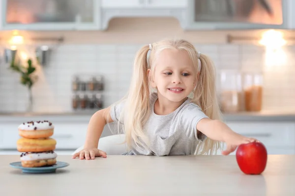 Маленькая Милая Девочка Выбирает Между Сладкими Пончиками Свежим Яблоком Кухне — стоковое фото