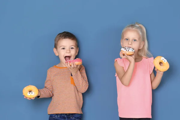 带甜甜甜圈的小孩子在颜色背景 — 图库照片