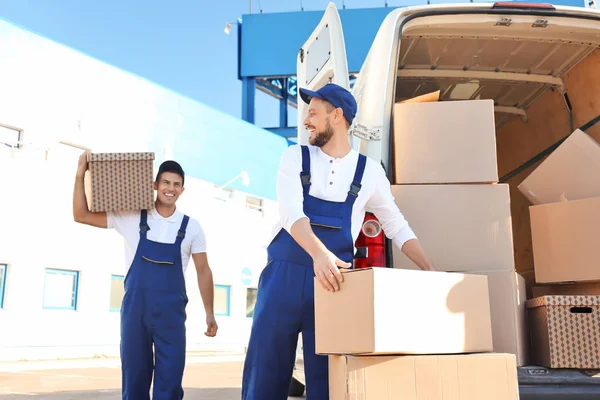 Delivery men unloading moving boxes from car — Stock Photo, Image