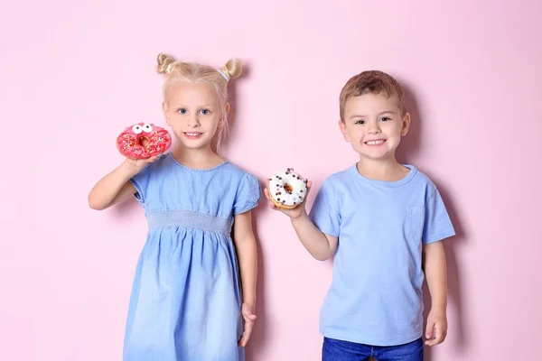 带甜甜甜圈的小孩子在颜色背景 — 图库照片
