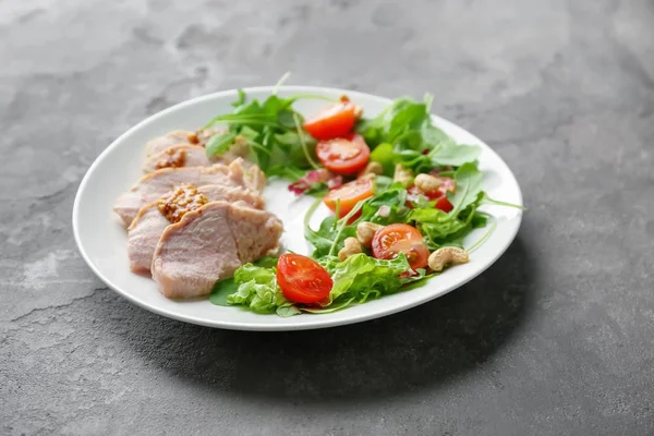 Płyta z mięsa i pyszne sałatki warzywne na szarym tle — Zdjęcie stockowe