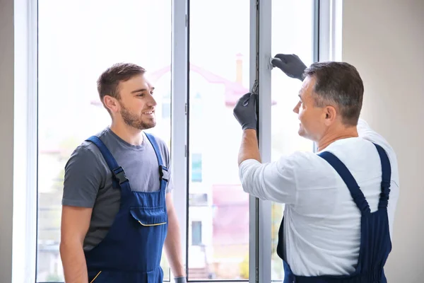 Trabalhador da construção civil com estagiário instalando janela em casa — Fotografia de Stock