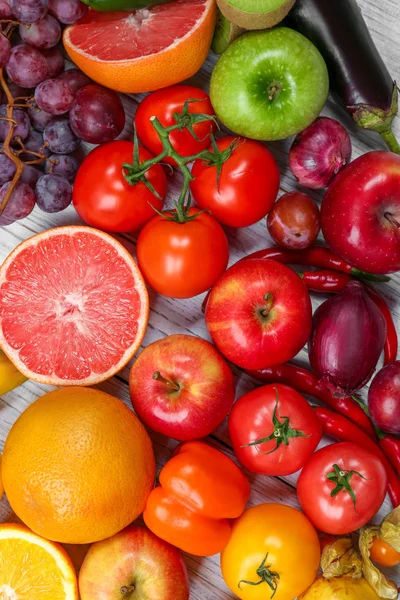 Creative composition made of fruits and vegetables in rainbow colors on wooden background