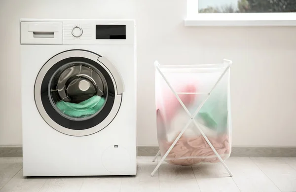 Laundry basket and washing machine indoors — Stock Photo, Image